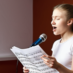 ** A student in a modern, well-equipped Moscow vocal studio, singing into a microphone with a focused expression. The instructor is giving constructive feedback, with sheet music visible in the background. Focus on the friendly and supportive atmosphere.

**